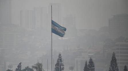Una bandera nacional hondureña ondea en medio de una densa capa de humo que cubre Tegucigalpa en mayo de 2024.