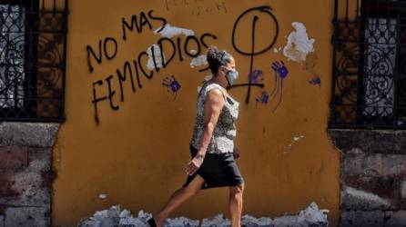 Una mujer camina frente a un mural que dice 'no más feminicidios', en la pared de un edificio en Centro Histórico, en Tegucigalpa.