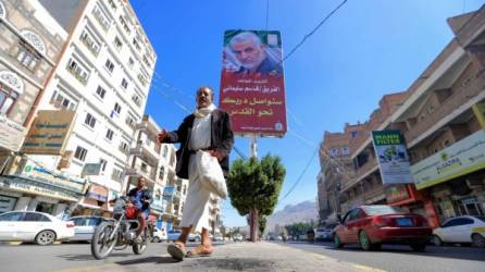 Un hombre yemení camina bajo un cartel del comandante militar iraní asesinado Qasem Soleimani en la capital, Sanaa, el 8 de enero de 2020. Soleimani y el jefe paramilitar iraquí Abu Mahdi al-Muhandis murieron en un ataque con aviones no tripulados estadounidenses cerca del aeropuerto internacional de Bagdad el 3 de enero. , provocando furia en Irán e Irak. / AFP / Mohammed HUWAIS