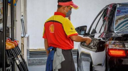 Ün empleado de gasolinera se apresta a llenar el tanque de un cliente en una estación de servicio ubicada en Bangkok, Tailandia.