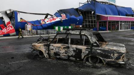 Un rescatista pasa junto a un coche averiado frente a un centro comercial destruido como resultado de un ataque con misiles, en Horlivka, Ucrania controlada por Rusia, el 25 de diciembre de 2023.