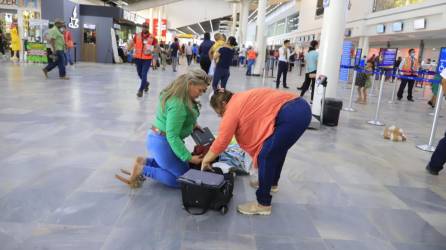 Personas de diferentes partes del país llegan al aeropuerto sampedrano y deben hacer cambios en sus maletas en el suelo porque no hay áreas modernas de descanso ni espera.