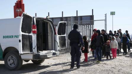 Un agente de la Patrulla Fronteriza de Estados Unidos carga a migrantes detenidos en una camioneta en la frontera de Estados Unidos y México.