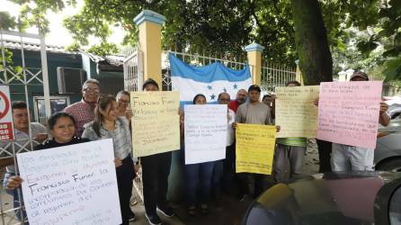 Empleados con pancartas en el portón del INA en San Pedro Sula.