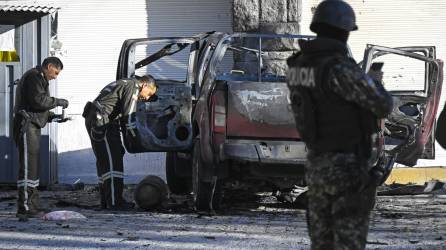 Agentes inspeccionan un auto bomba que explotó anoche en Quito.