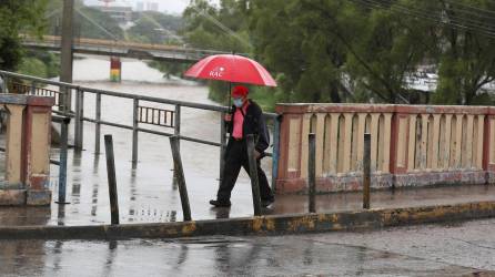 Un ciudadano camina mientras al fondo se ve el elevado nivel del río Choluteca, en Tegucigalpa (Honduras), en una fotografía de archivo. EFE/Gustavo Amador