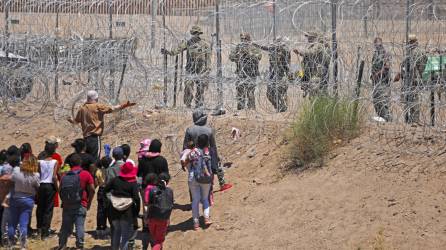 Un grupo de migrantes habla con agentes de la Guardia Nacional de Texas en la frontera entre EEUU y México.