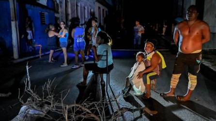 Los residentes cubanos se reúnen afuera en un vecindario bloqueado en medio de un apagón eléctrico prolongado después del huracán Ian en La Habana.