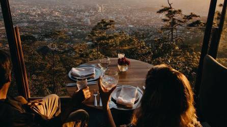 Fotografía muestra a una pareja comiendo en el restaurante La Cumbre. Al fondo se observa la ciudad de Tegucigalpa, Honduras.