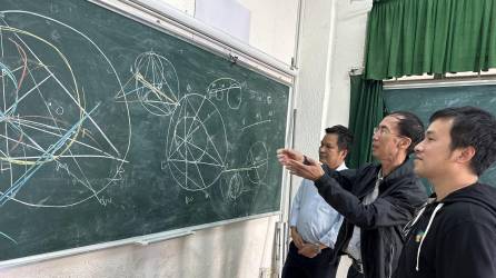 Thang Luong (der.) escudriña un problema de geometría con dos de sus antiguos profesores en Ho Chi Minh, Vietnam.