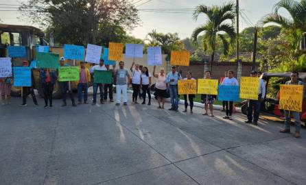 Personas muestras sus rótulos mientras protestan frente al Parque Arqueológico de Copán Ruinas.