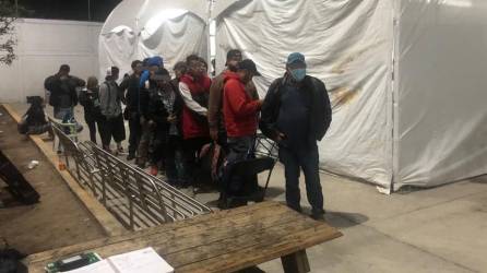 Un grupo de migrantes esperan para entrar a un albergue en Ciudad Juárez.