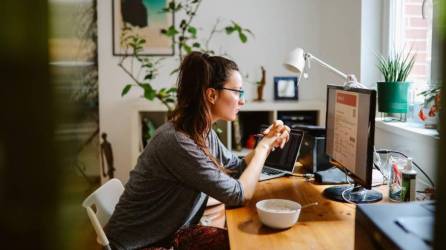 Una mujer sentada frente a la computadora haciendo teletrabajo.