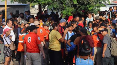 Miembros del Instituto Nacional de Migración (INM) dialogan con migrantes instalados en un campamento improvisado en una cancha deportiva hoy, en el municipio de Mapastepec, estado de Chiapas.