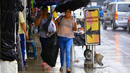 Mujeres caminan con sombrilla en el centro de San Pedro Sula.