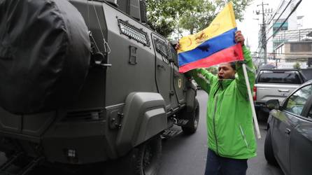 Un hombre exhibe una bandera mientras pasa un vehículo blindado donde es trasladado el exvicepresidente ecuatoriano Jorge Glas, este sábado en Quito (Ecuador).