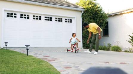 Un hombre junto a una niña en la zona exterior de una vivienda.