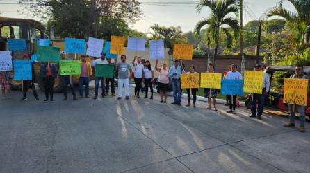 Personas muestras sus rótulos mientras protestan frente al Parque Arqueológico de Copán Ruinas.