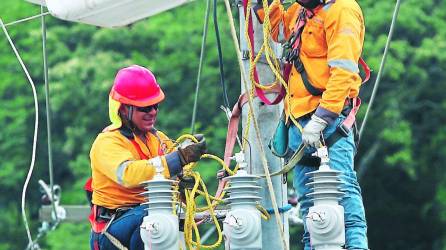Dos técnicos de la Empresa Energía Honduras realizan labores de instalación de transformadores.