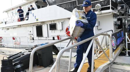 Fotografía cedida por la Guardia Costera de Estados Unidos donde aparece un miembro de la tripulación del buque guardacostas Margaret Norvell mientras descarga paquetes decomisados con más de una tonelada de cocaína, valorada en más de 32 millones de dólares hoy, a Miami, Florida.