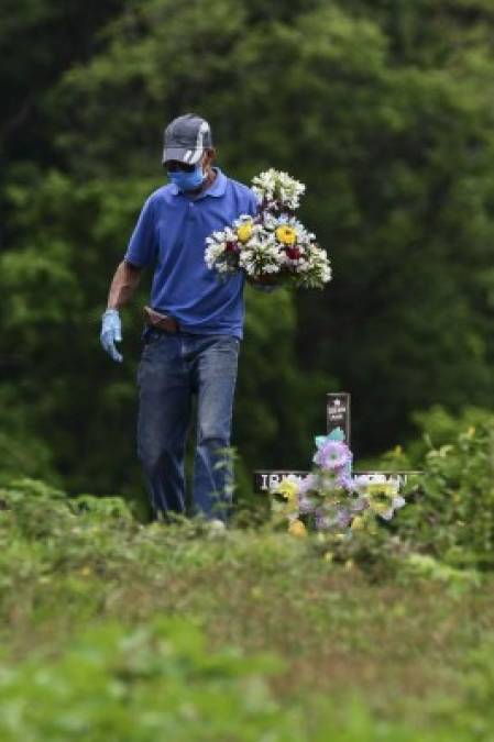 A man carries flowers during the burial of a COVID-19 victim at an annex of the Parque Memorial Jardin de Los Angeles cemetery, acquired by the municipality to bury people who died from the new coronavirus, 14 km north of Tegucigalpa on June 17, 2020. - Honduras has so far registered 9,658 contagions and 478 deaths from COVID-19. (Photo by ORLANDO SIERRA / AFP)