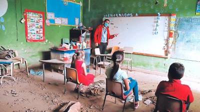 Niños hondureños recibiendo clases en una aula deteriorada.