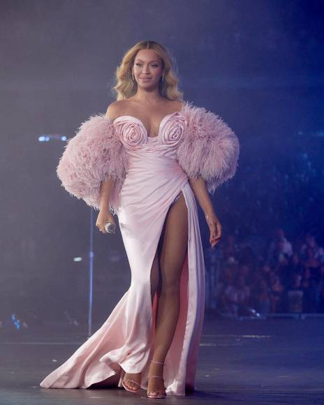 Beyoncé también ha lucido en múltiples ocasiones grandes atuendos muy femeninos en color rosa. Este fue uno de los más recientes en un concierto, la voluptuosa cantante resaltó su cuerpo con un vestido largo, de pierna abierta, con rosas en la parte del pecho y mangas de pelusa, dejando sus hombros al descubierto, toda una diva coqueta.