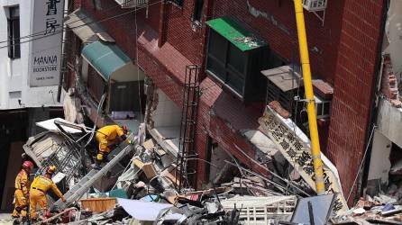 Rescatistas buscan sacar a las personas atrapadas bajo los escombros en los edificios derrumbados tras el sismo.