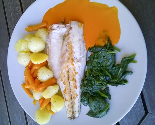 Fish dish with vegetables and red pepper sauce