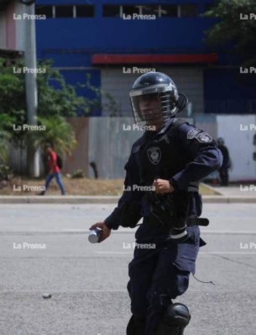 Uniformado a punto de lanzar una bomba lacrimógena.