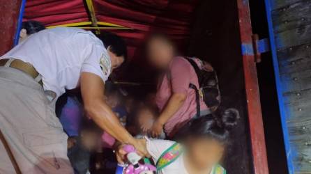 Un funcionario de migración ayuda a bajar a varios niños del tractocamión.