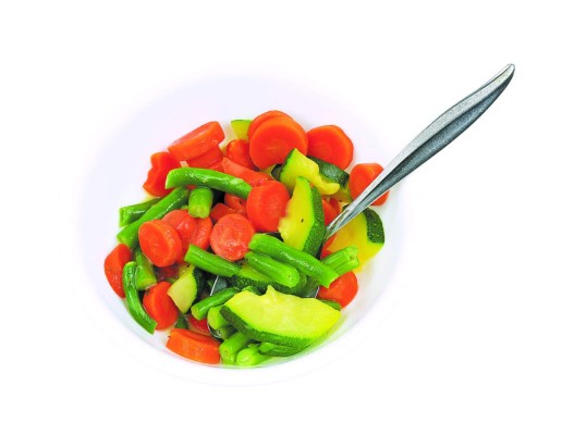 A white bowl filled with cooked zucchini, green beans and carrots in a butter sauce with a serving spoon.