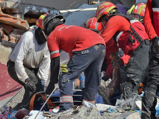 Rescuers remove a corpse from the rubble in Manta, Ecuador on April 19, 2016, two days after the 7.8-magnitude quake that struck the region.Rescuers and desperate families clawed through the rubble Monday to pull out survivors of an earthquake that killed at least 413 people and destroyed towns in a tourist region of Ecuador. / AFP PHOTO / LUIS ACOSTA