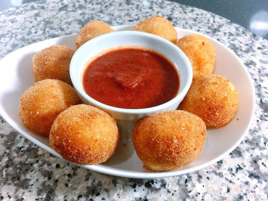 Servir las bolitas de yuca frita con chicharrón acompañadas de salsa de tomate o el aderezo de su preferencia.