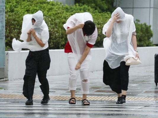 People walk against strong winds in Nagoya on September 4, 2018, as Typhoon Jebi made landfall around midday in southwestern Japan.The strongest typhoon to hit Japan in 25 years made landfall on September 4, the country's weather agency said, bringing violent winds and heavy rainfall that prompted evacuation warnings. / AFP PHOTO / JIJI PRESS / JIJI PRESS / Japan OUT