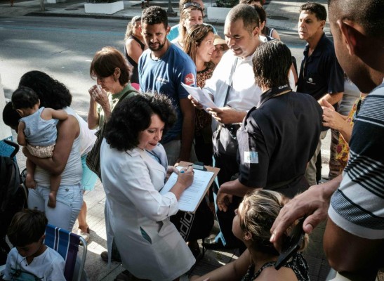 People queue outside a public health center to be vaccinated against yellow fever in Rio de Janeiro, Brazil, on March 17, 2017. Rio de Janeiro's state is vaccinating its entire population against yellow fever in response to an outbreak that has killed at least 113 people around Brazil. / AFP PHOTO / Yasuyoshi Chiba