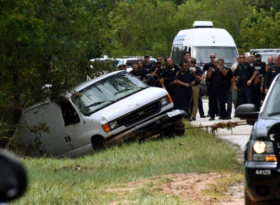 Police investigators watch as the van containing the six members of the the Saldivar family who died is towed to the road after they crashed their van into Greens Bayou as they tried to flee Hurricane Harvey during heavy flooding in Houston, Texas on August 30, 2017. / AFP PHOTO / MARK RALSTON