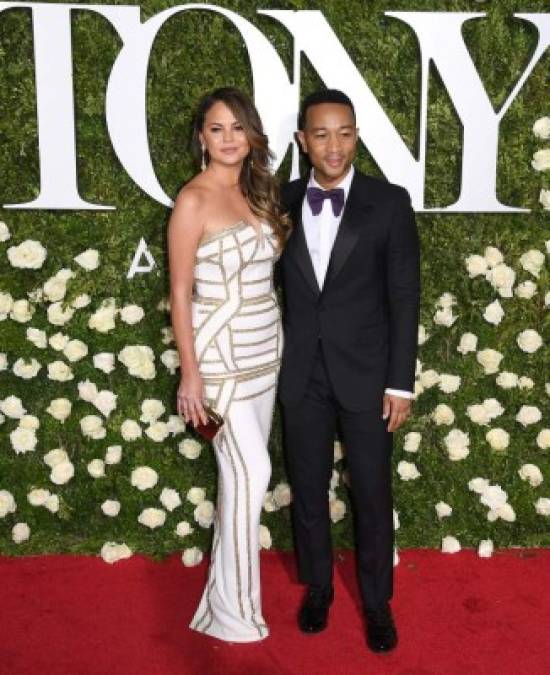 John Legend y Chrissy Teigen se miraban radiantes en la alfombra roja mientras sonreían y posaban para las fotos juntos. Teigen deslumbró con un vestido blanco con adornos de dorados, mientras que Legend mantuvo su aspecto clásico en un espléndido traje negro.