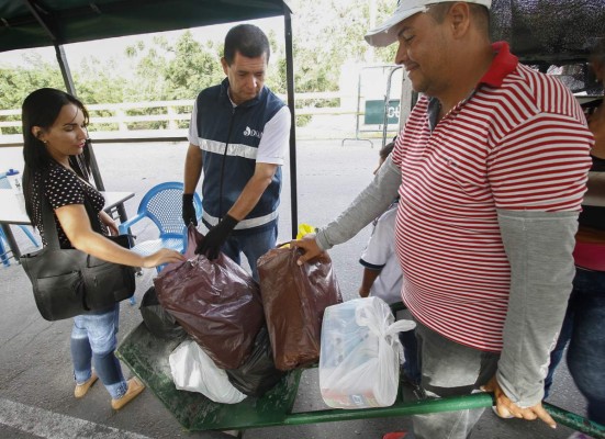 Venezuelans carry groceries purchased in Colombia whilst crossing the border back to Venezuela in Cucuta on June 6, 2016.Colombia is willing to expand the humanitarian corridor from its border with Venezuela, closed by Venezuela's President Nicolas Maduro almost a year ago, to alleviate the 'problems' of shortages of food and medicine in the neighboring country, said on Wednesday the Chancellor, María Ángela Holguín. / AFP PHOTO / Schneyder Mendoza