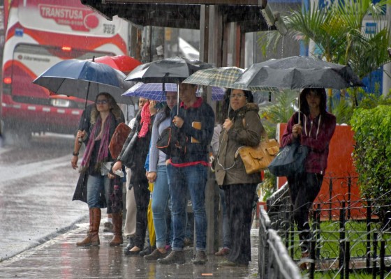 Locals holding umbrellas wait at a bus stop during a downpour caused by tropical storm Nate in Cartago, 25 kilometres East of San Jose on October 5, 2017.Costa Rica is under a National Emergency decree due to heavy rains and winds that already left two dead and 6 dissapeared, while several roads and bridges were damaged, and rockslides blocked access to some villages. / AFP PHOTO / EzequielBECERRA