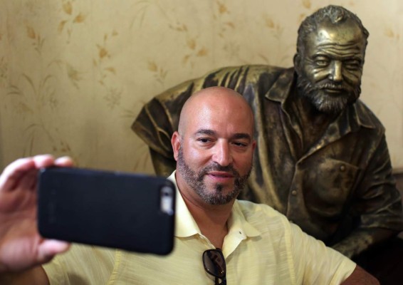 -FOTODELDIA- HAB06. LA HABANA (CUBA) 16/08/2017.- Un turista se toma un selfie junto a la estatua del escritor estadounidense Ernest Hemingway hoy, miércoles 16 de agosto, en el famoso restaurante El Floridita, en la Habana (Cuba). Azúcar, jugo de limón, ron, hielo frapeado y unas gotas de marrasquino se conjugan en la alquimia del daiquiri clásico, un cóctel de fama mundial que atrae cada año a miles de personas a su lugar de creación, el Floridita de La Habana, que ahora celebra sus doscientos años abierto. Pero es difícil decidir si el mejor embajador de este bicentenario bar de La Habana Vieja -hoy propiedad del Estado cubano- es su cóctel estrella o lo es el premio Nobel de Literatura Ernest Hemingway, visitante asiduo durante sus largas estancias en Cuba. EFE/Alejandro Ernesto