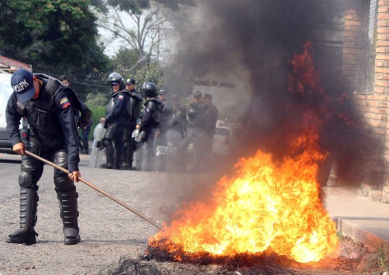 A riot policeman tries to put out a barricade set on fire by students during a protest against Venezuelan President Nicolas Maduro, in San Cristobal, Venezuela, on March 9, 2016. Venezuela's opposition called for the 'largest movement that has ever existed' to oust Maduro, vowing to pursue all means to force him from power, including a referendum and protests. AFP PHOTO / GEORGE CASTELLANO