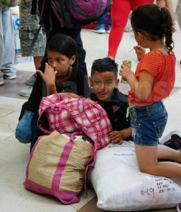 Tres niños esperan abordar un bus en la Gran Terminal de San Pedro Sula.<br/><br/>