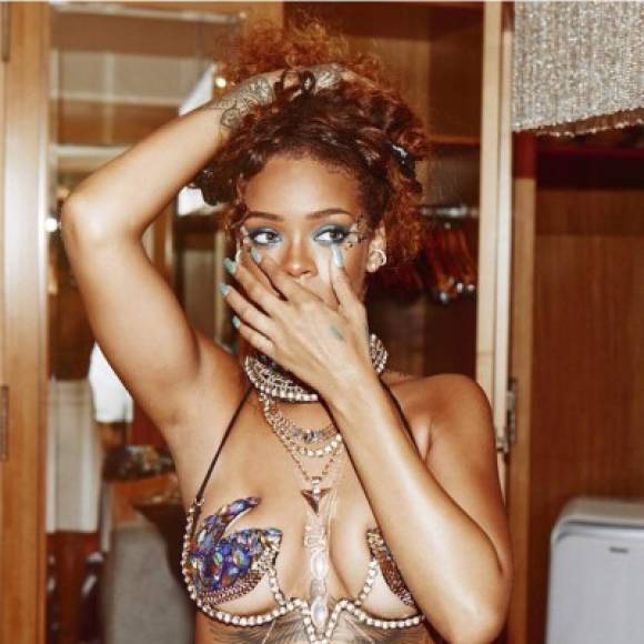 Rihanna sus rizos color rojo y un maquillaje azulado.