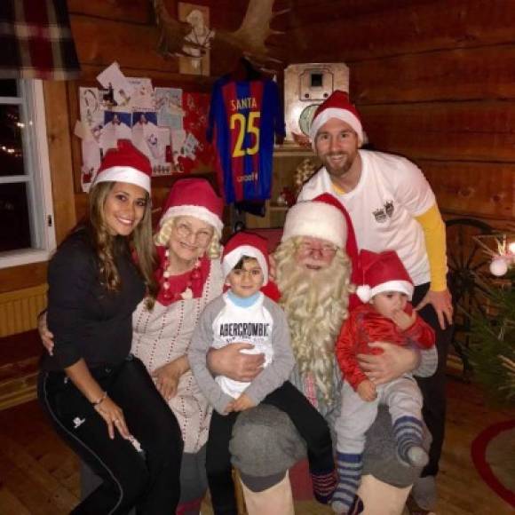 Lionel Messi, Antonella Roccuzzo y sus dos hijos, con Papá y Mamá Noel y la camiseta con el 25 del Barcelona al fondo.