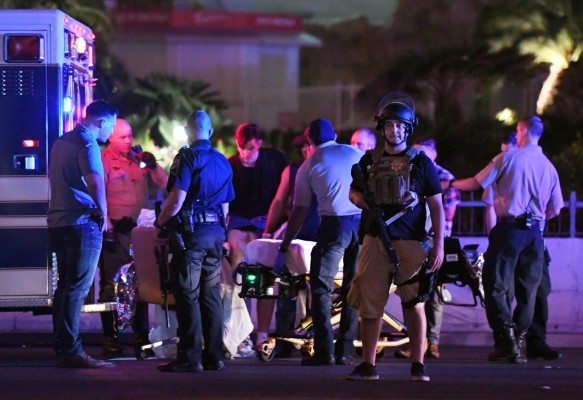 LAS VEGAS, NV - OCTOBER 02: Police officers stand by as medical personnel tend to a person on Tropicana Ave. near Las Vegas Boulevard after a mass shooting at a country music festival nearby on October 2, 2017 in Las Vegas, Nevada .A gunman has opened fire on a music festival in Las Vegas, leaving over 20 people dead. Police have confirmed that one suspect has been shot. The investigation is ongoing. Ethan Miller/Getty Images/AFP== FOR NEWSPAPERS, INTERNET, TELCOS & TELEVISION USE ONLY ==