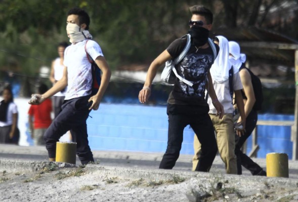 Riot police shoot tear gas during clashes with students of the National Autonomous University of Honduras (UNAH) demanding justice for the murder of indigenous leader, coordinator of the Council of Popular and Indigenous Organizations of Honduras (COPINH), and environmental activist Berta Caceres in Tegucigalpa, on March 3, 2020. - Caceres was murdered at her house by unidentified armed gunmen on March 2, 2016. (Photo by ORLANDO SIERRA / AFP)