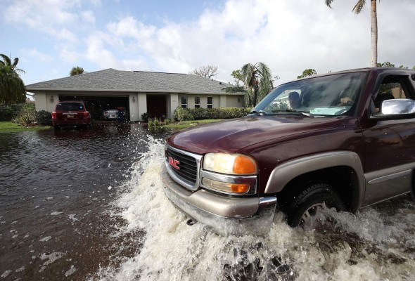 BONITA SPRINGS, FL - SEPTEMBER 11: A driver guides his pickup truck through a neighborhood flooded by Hurricane Irma on September 11, 2017 in Bonita Springs, Florida. Hurricane Irma made landfall in the Florida Keys as a Category 4 storm on Sunday, lashing the state with 130 mph winds as it moved up the coast. Mark Wilson/Getty Images/AFP== FOR NEWSPAPERS, INTERNET, TELCOS & TELEVISION USE ONLY ==