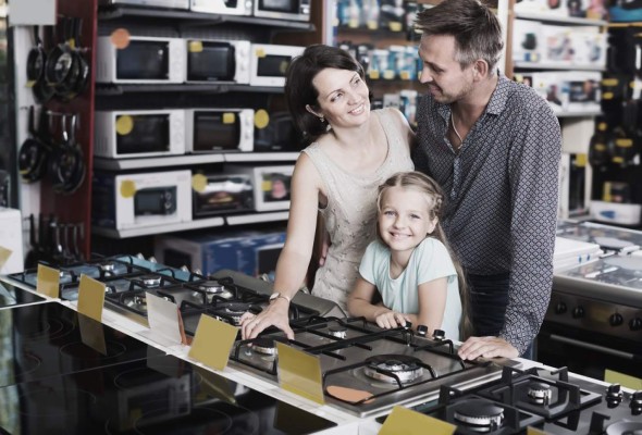 Young family of three choosing new cooking plate in household store