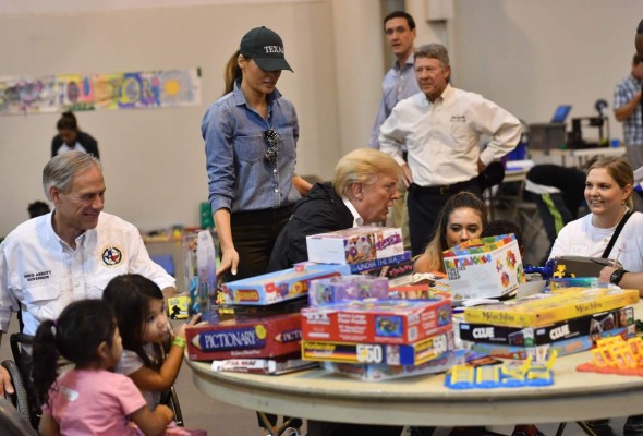 US President Donald Trump, with Texas Gorvernor Greg Abbott (L) and US First Lady Melania Trump (2nd L) visits Hurricane Harvey victims at NRG Center in Houston on September 2, 2017. / AFP PHOTO / Nicholas Kamm